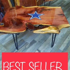 May include: A wooden table with a blue star design on the top. The table has a natural wood finish and is supported by black hairpin legs. The table is sitting on a wood floor.