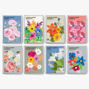 Könnte beinhalten: Ein Satz von acht bunten Postern mit floralen Designs und dem Text "Flower Market" mit dem Städtenamen darunter. Die Poster sind in Silber gerahmt und haben einen weißen Hintergrund.