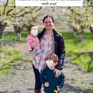 May include: A woman with two children in a park setting. The woman is wearing a plaid shirt, a black jacket, and brown boots. The children are wearing a pink sweater, blue jeans, and green boots. The woman is holding the younger child in her arms. The older child is standing next to her. The background is a blurred image of trees and grass.