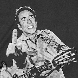 Könnte beinhalten: Ein dunkelgraues T-Shirt mit einem Schwarzweißbild von Nicolas Cage, der den Mittelfinger zeigt, während er Gitarre spielt. Der Text "CAGE" ist in Weiß unter dem Bild gedruckt.