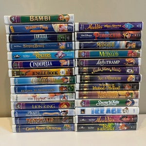 Peut inclure: Une pile de 20 cassettes VHS de films d'animation Disney classiques, dont Bambi, Aladdin, La Petite Sirène, Cendrillon et Le Roi Lion. Les cassettes sont disposées verticalement, avec les titres face avant.