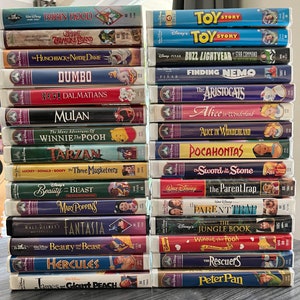Peut inclure: Une pile de cassettes VHS Disney vintage avec des classiques animés comme "Toy Story", "Le Roi Lion" et "La Belle et la Bête". Les cassettes ont des couvertures colorées avec des titres de films et des illustrations de personnages. La collection comprend des titres des collections Disney Classics et Pixar.
