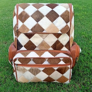 May include: A brown and white patchwork leather backpack with multiple pockets and zippers.