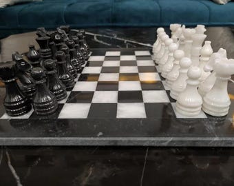 Può includere: Un set da scacchi in marmo bianco e nero con pezzi bianchi e neri su una scacchiera in marmo nero.