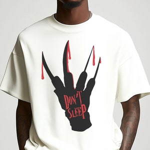K&ouml;nnte beinhalten: Wei&szlig;es T-Shirt mit einer schwarzen Silhouette einer Hand mit blutigen Krallen und dem Text "Don't Sleep" in Rot.
