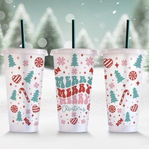 May include: Three clear plastic cups with lids and straws. Each cup has a different design featuring a red and white candy cane, red hearts, snowflakes, and green Christmas trees. The text "Merry Merry Christmas" is printed on one of the cups.