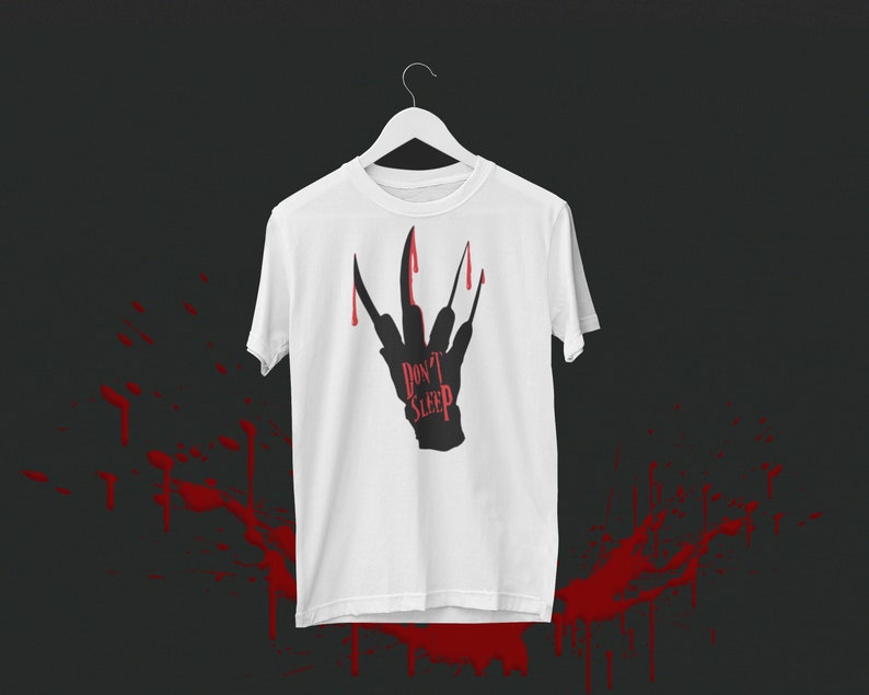 K&ouml;nnte beinhalten: Wei&szlig;es T-Shirt mit einer schwarzen Silhouette einer Hand mit Krallen und tropfendem Blut. Der Text "Don't Sleep" ist auf die Hand geschrieben.