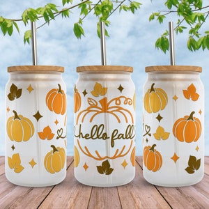May include: Three white tumblers with a fall theme. Each tumbler has a brown lid and a stainless steel straw. The tumblers are decorated with orange pumpkins, brown leaves, and the text "hello fall".