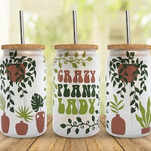 May include: Three white stainless steel tumblers with a wood lid and a straw. Each tumbler features a different design of green plants and the text "Crazy Plant Lady".