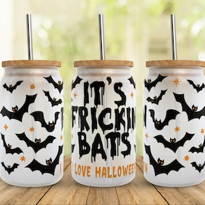 May include: Three white glass can-shaped tumblers with bamboo lids and silver straws. The tumblers are decorated with black bat silhouettes and orange stars. One tumbler has the text "IT'S FRICKIN BATS I LOVE HALLOWEEN".