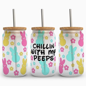 May include: Three clear glass tumblers with a white background and a pattern of yellow, pink, and blue bunny-shaped marshmallow candies and pink flowers. The middle tumbler has the text "Chillin with my peeps" in black lettering.