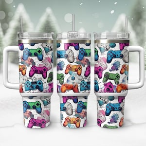 May include: Three white stainless steel tumblers with lids and handles. Each tumbler features a colorful watercolor pattern of video game controllers.