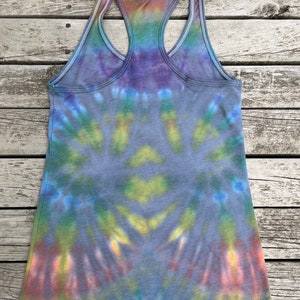 K&ouml;nnte beinhalten: Batik-Tanktop mit einem Regenbogenmuster in Blaut&ouml;nen, Gr&uuml;n, Gelb, Orange und Lila. Das Tanktop hat einen Racerback-Stil und ist mit "Medium 2" gekennzeichnet.