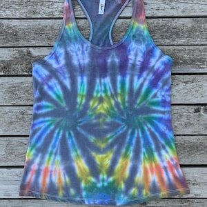 K&ouml;nnte beinhalten: Ein Batik-Tanktop in Blaut&ouml;nen, Lila, Gr&uuml;n, Gelb und Orange. Das Tanktop hat einen Racerback-Stil und ist mit "X-Large" gekennzeichnet.