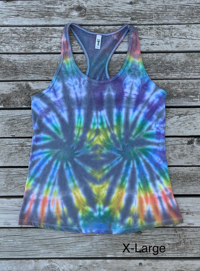 K&ouml;nnte beinhalten: Ein Batik-Tanktop in Blaut&ouml;nen, Lila, Gr&uuml;n, Gelb und Orange. Das Tanktop hat einen Racerback-Stil und ist mit "X-Large" gekennzeichnet.