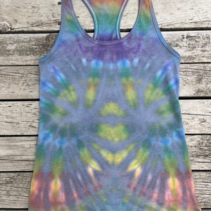K&ouml;nnte beinhalten: Ein Batik-Tanktop mit einem Regenbogenmuster in Blaut&ouml;nen, Gr&uuml;n, Gelb, Orange und Rosa. Das Tanktop hat einen Racerback-Stil und ist aus einem weichen, bequemen Stoff gefertigt. Der Text "Medium 2" ist in der oberen rechten Ecke des Bildes sichtbar.