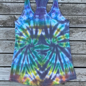 K&ouml;nnte beinhalten: Ein Batik-Tanktop mit einem Wirbelmuster in Blaut&ouml;nen, Gr&uuml;n, Gelb und Braun. Das Tanktop hat einen Racerback-Stil und ist mit "Large" gekennzeichnet.