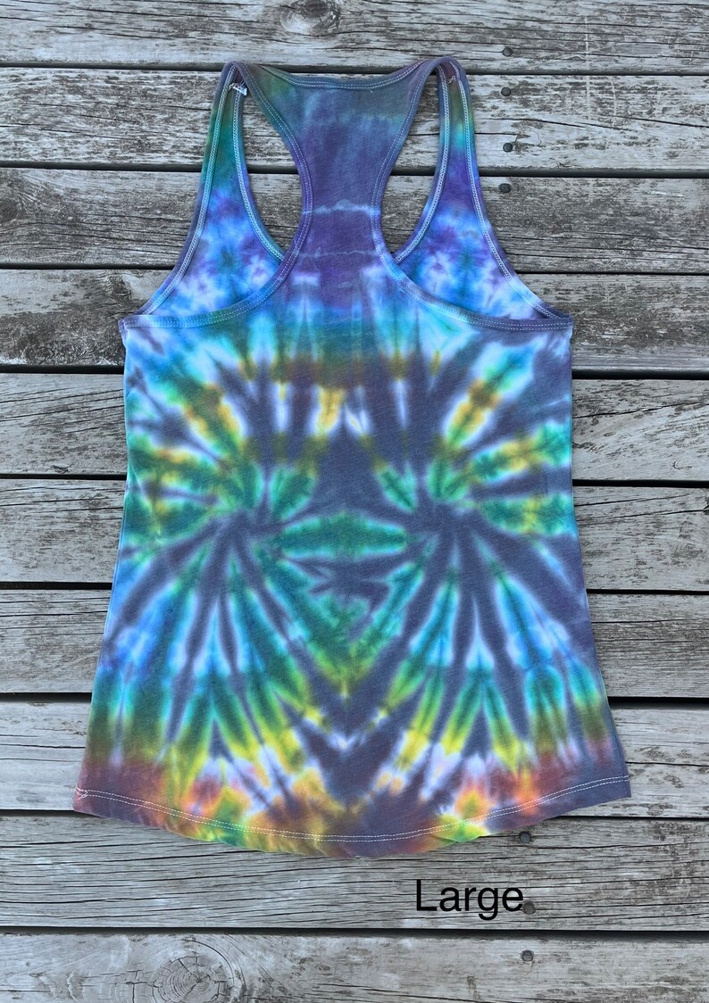 K&ouml;nnte beinhalten: Ein Batik-Tanktop mit einem Wirbelmuster in Blaut&ouml;nen, Gr&uuml;n, Gelb und Braun. Das Tanktop hat einen Racerback-Stil und ist mit "Large" gekennzeichnet.