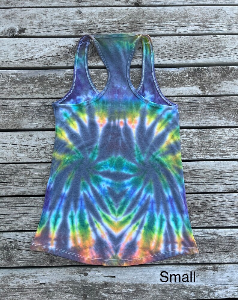K&ouml;nnte beinhalten: Ein Batik-Tanktop mit einem Regenbogenmuster in Blaut&ouml;nen, Gr&uuml;n, Gelb und Orange. Das Tanktop ist aus einem weichen, bequemen Stoff gefertigt und hat einen Racerback-Stil. Das Tanktop ist in Gr&ouml;&szlig;e S erh&auml;ltlich.