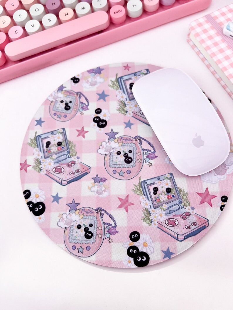 May include: A pink and white mousepad with a checkered pattern and a repeating design of a pink and blue handheld game console, a pink and purple charm with the word "My Melody" on it, and black and white eyes. A white wireless mouse is sitting on the mousepad.