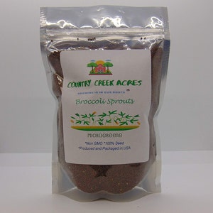 May include: A clear plastic bag filled with small brown seeds. The bag has a white label with the text "COUNTRY CREEK ACRES", "GROWING IS IN OUR ROOTS", "Broccoli Sprouts", "MICROGREENS", "*Non GMO *100% Seed", and "*Produced and Packaged in USA".