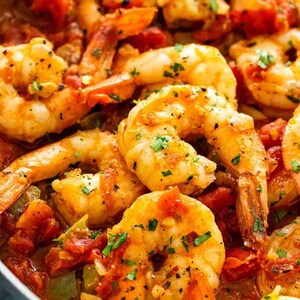 May include: A close-up of a skillet filled with cooked shrimp in a tomato sauce. The shrimp are plump and juicy, and the sauce is rich and flavorful. The shrimp are garnished with fresh parsley.