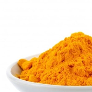 May include: A white bowl filled with bright yellow turmeric powder.