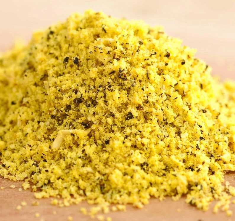 Peut inclure: Gros plan sur un m&eacute;lange d'assaisonnement jaune avec de petites taches sombres. L'assaisonnement est empil&eacute; haut et semble sec et granulaire.