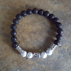 Bracelet blanc de diffuseur semi-précieux de pierre gemme et de lave noire de Howlite avec une tête tibétaine de bouddha d’argent