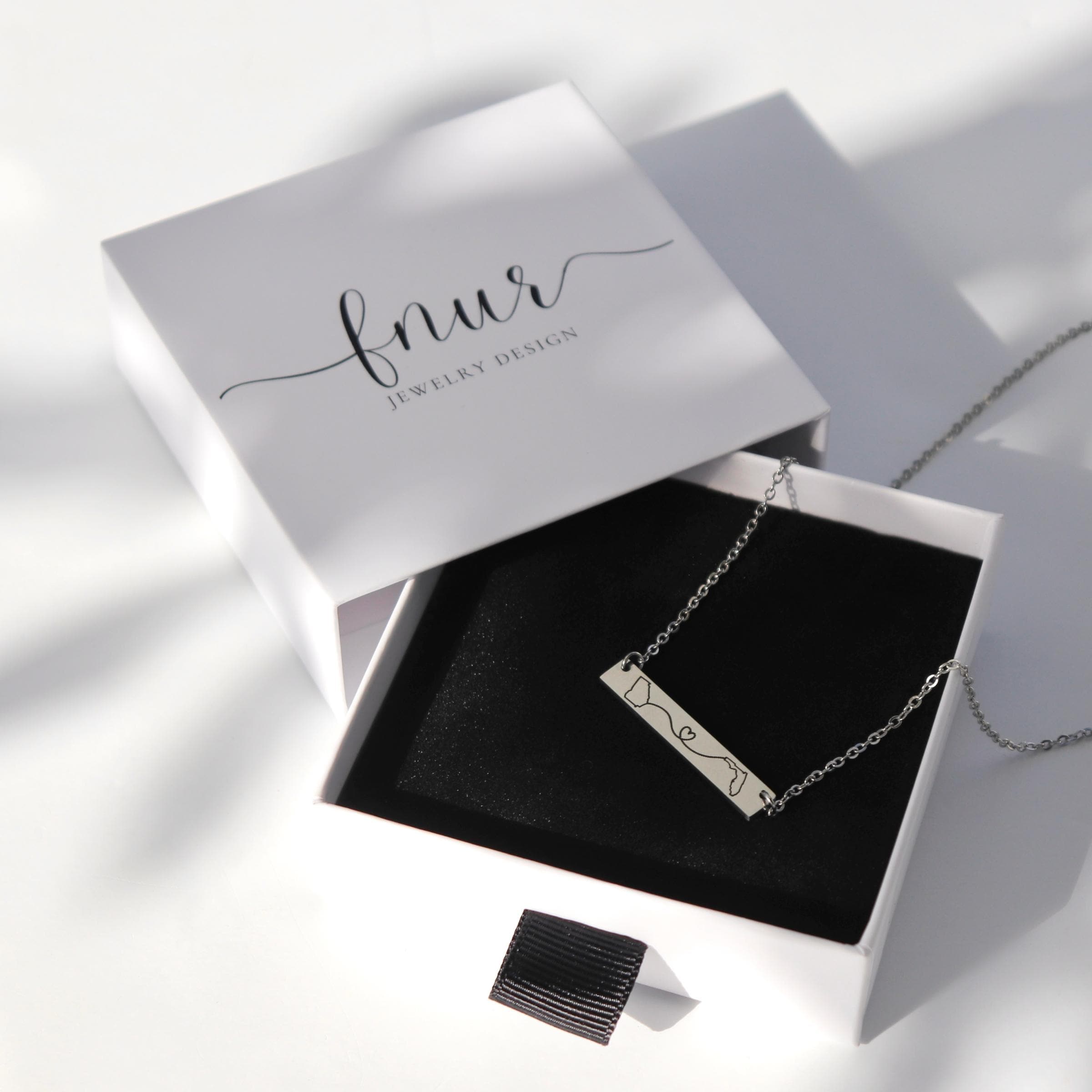 selection of gold silver and rose gold state necklaces arranged on white display