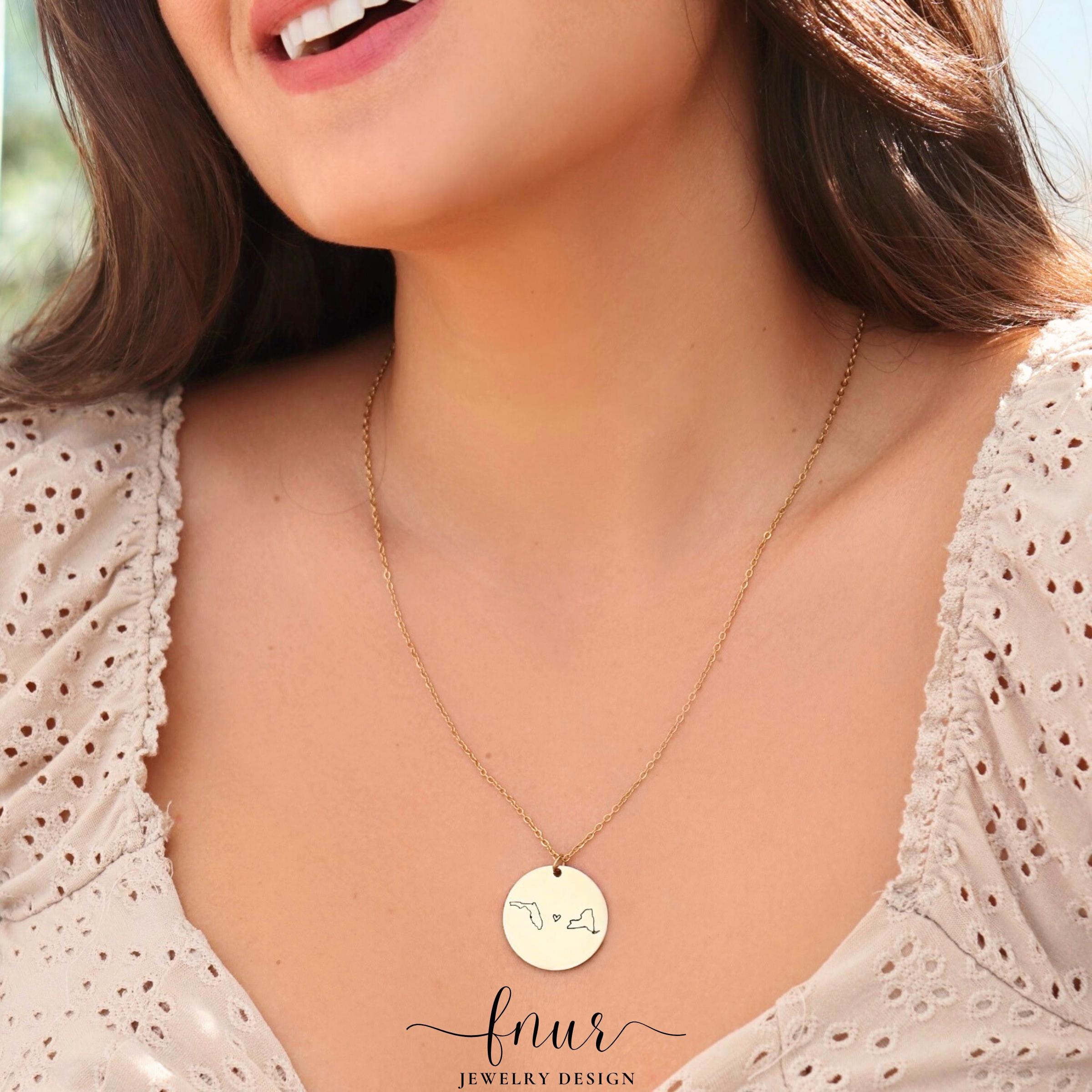 silver finish long distance friendship necklace resting on elegant professional jewelry display stand