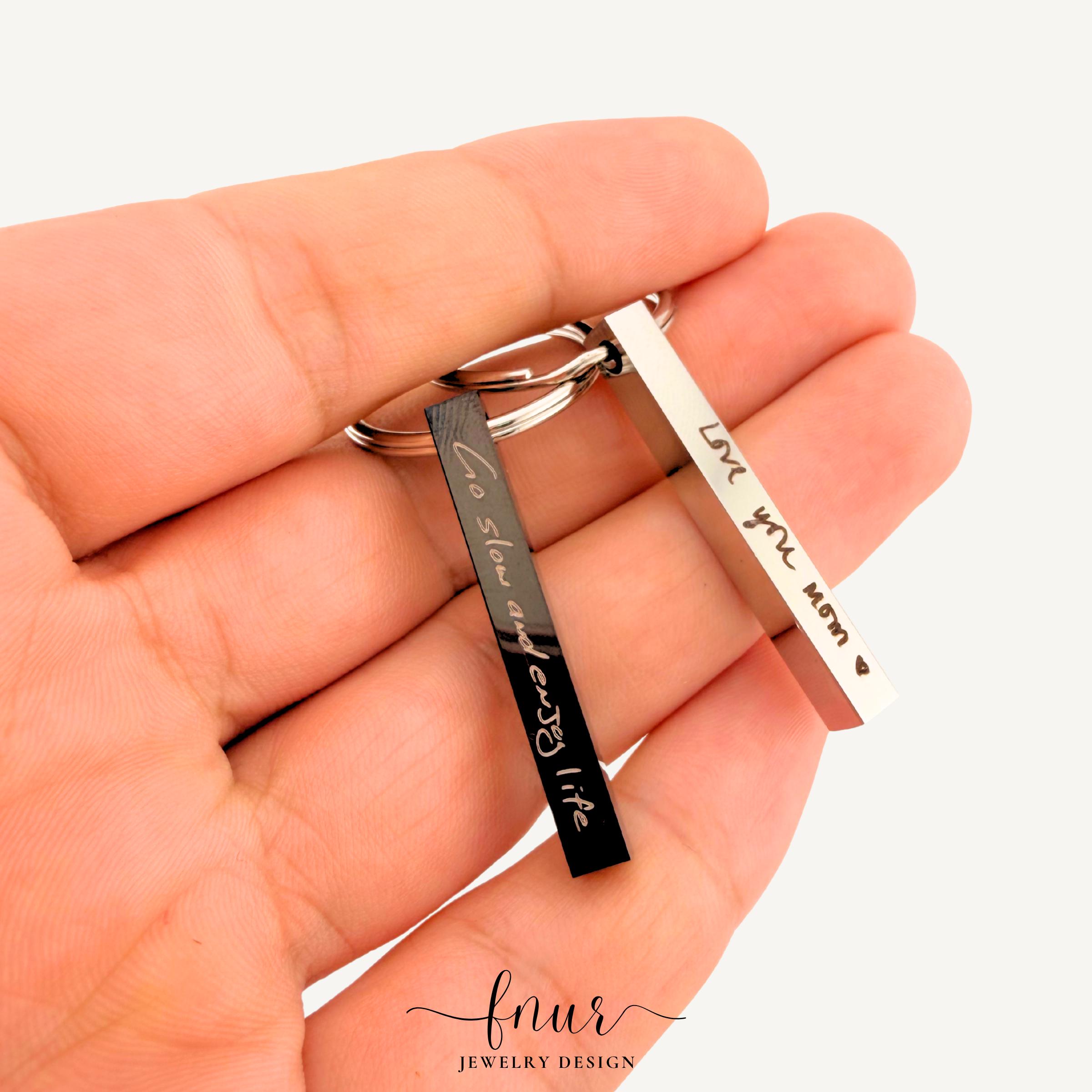 Angled perspective of custom signature keychain bar revealing deep laser etching and high quality craftsmanship