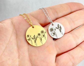 Op de afbeelding: Twee kettingen met delicate kettingen en ronde hangers met gegraveerde bloemenmotieven. De hanger aan de linkerkant is goud en de hanger aan de rechterkant is zilver.