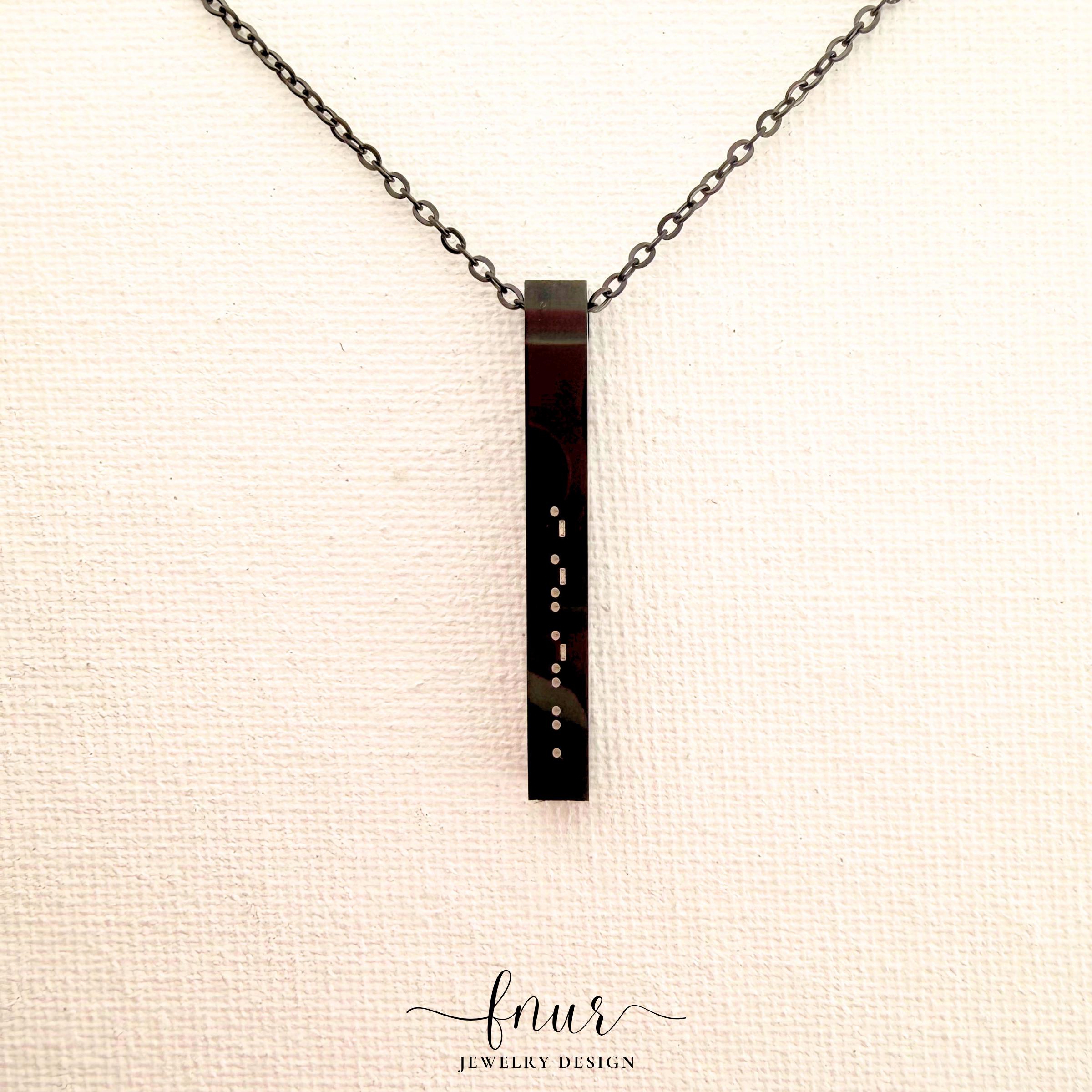 brushed silver finish morse code bar necklace displayed on table