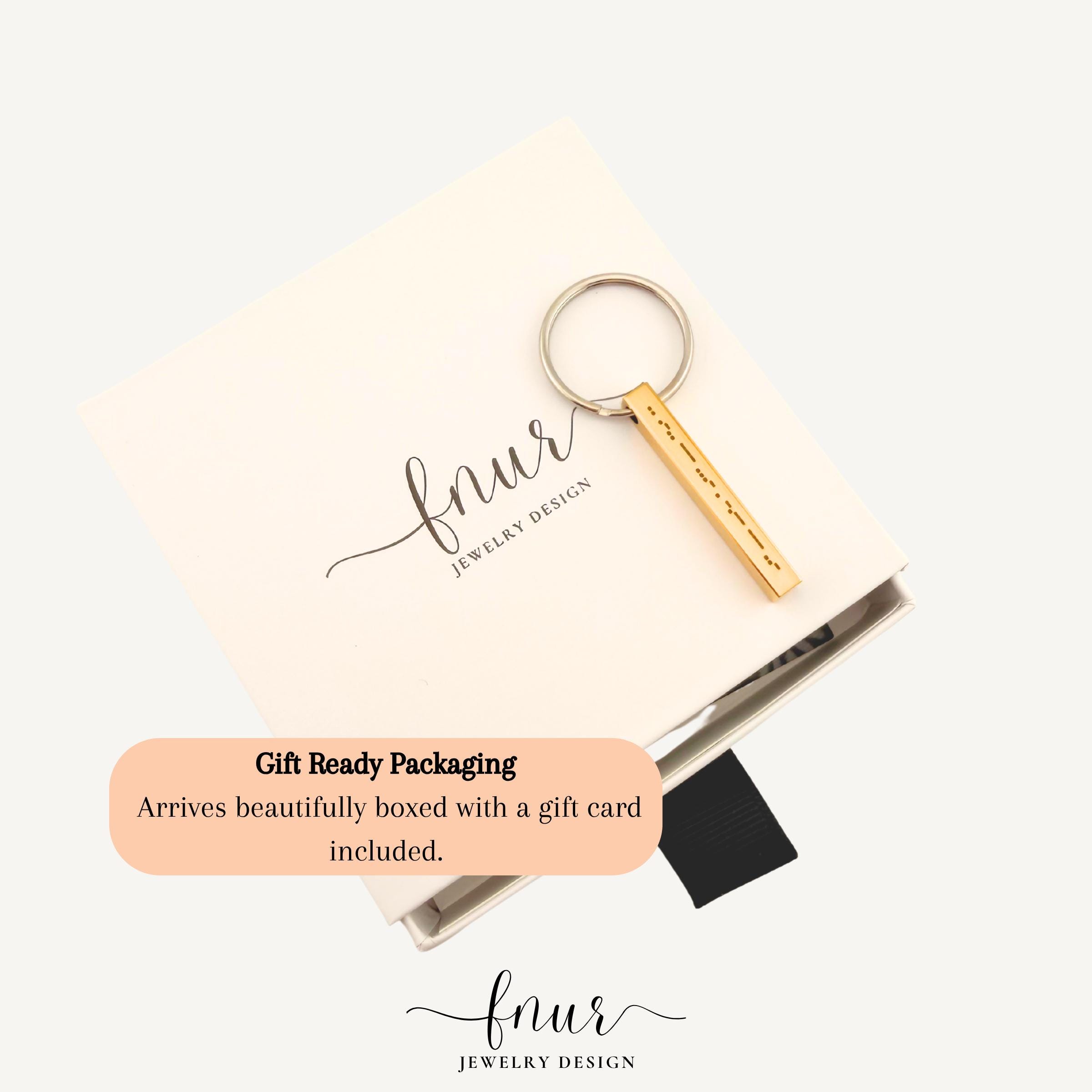 lifestyle flat lay of morse code bar keychain displayed with minimalist accessories and keys