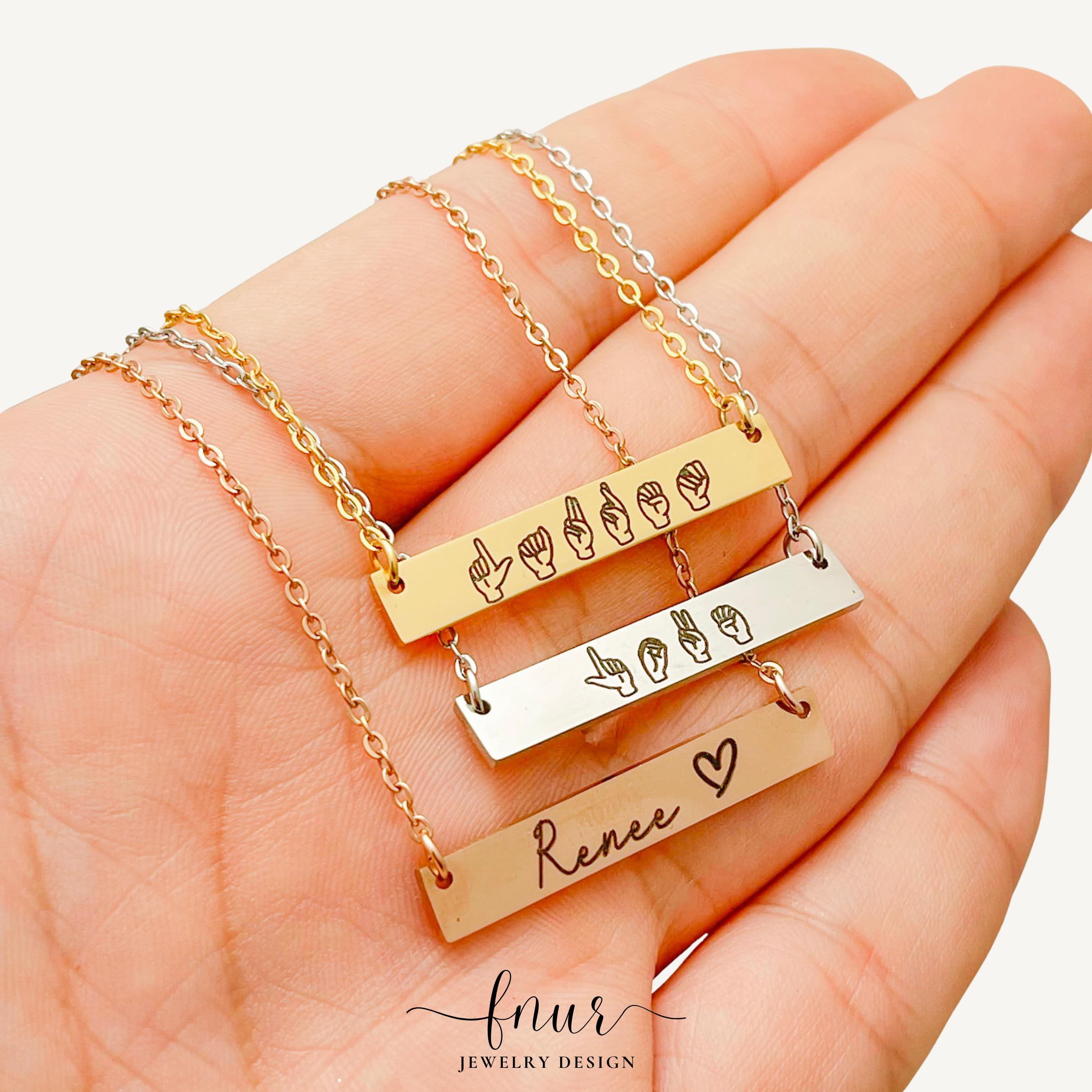 elegant gold finish asl name bar pendant reflecting soft boutique jewelry studio lighting