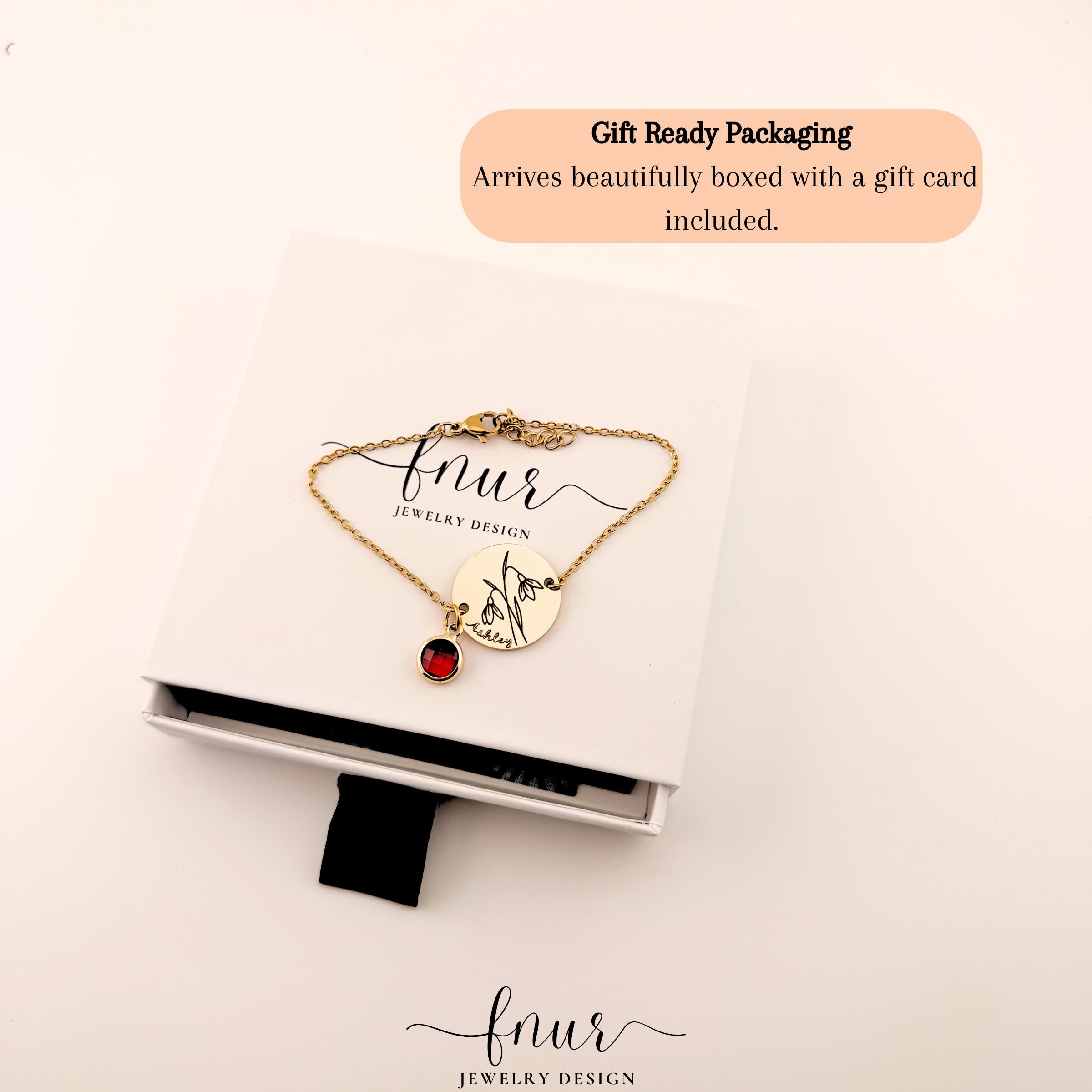 Flat lay of custom birth month bracelet surrounded by delicate floral elements and jewelry