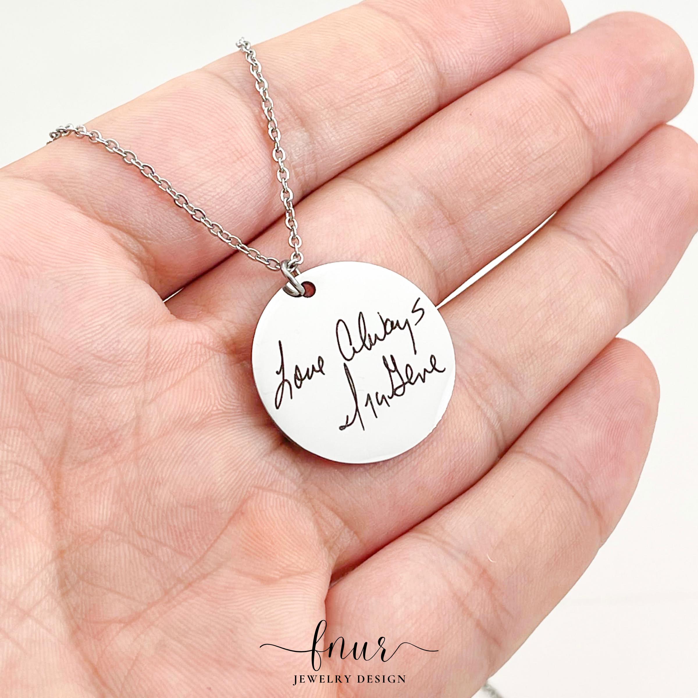 bright studio shot of gold handwriting necklace catch reflecting light against white background