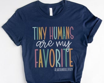 Puede incluir: Una camiseta azul marino con el texto "Tiny Humans are my Favorite" en colores arcoíris. El texto está en una fuente divertida e incluye el hashtag #laboranddelivery.