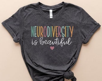 May include: A dark gray t-shirt with the text "Neurodiversity is beautiful" in colorful letters. A small pink heart is below the text.