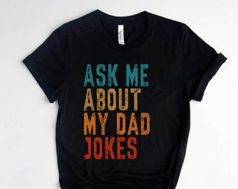 May include: Black t-shirt with a vintage-style graphic that says "Ask Me About My Dad Jokes".
