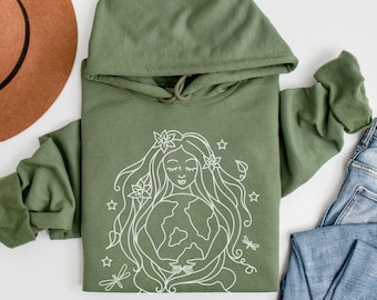 May include: A green hooded sweatshirt featuring a white outline drawing of a woman holding the Earth. The woman has long hair with flowers and stars around her. The drawing is on the front of the sweatshirt.