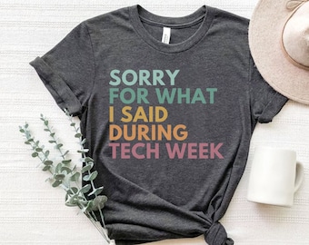 May include: A dark grey t-shirt with the text "SORRY FOR WHAT I SAID DURING TECH WEEK" printed in rainbow colors.