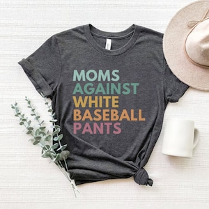 May include: A dark grey t-shirt with the text "MOMS AGAINST WHITE BASEBALL PANTS" printed in colourful letters.