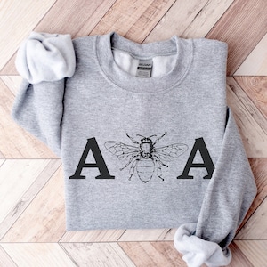 May include: Gray sweatshirt with a black bee and the letters "A A" printed on the front.