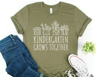 May include: A green t-shirt with a white graphic of potted plants and the text "Kindergarten Grows Together".