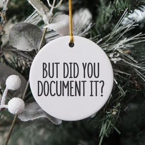 May include: White ceramic Christmas ornament with black text that reads "But did you document it?"
