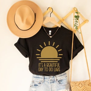 May include: Black t-shirt with a gold sun graphic and the text "It's a beautiful day to do labs".