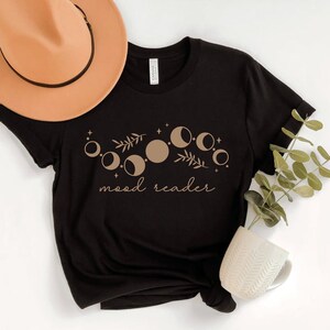 May include: Black t-shirt with a brown moon phases design and the text "mood reader".