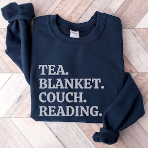 May include: A navy blue sweatshirt with the text "TEA. BLANKET. COUCH. READING." printed in white.